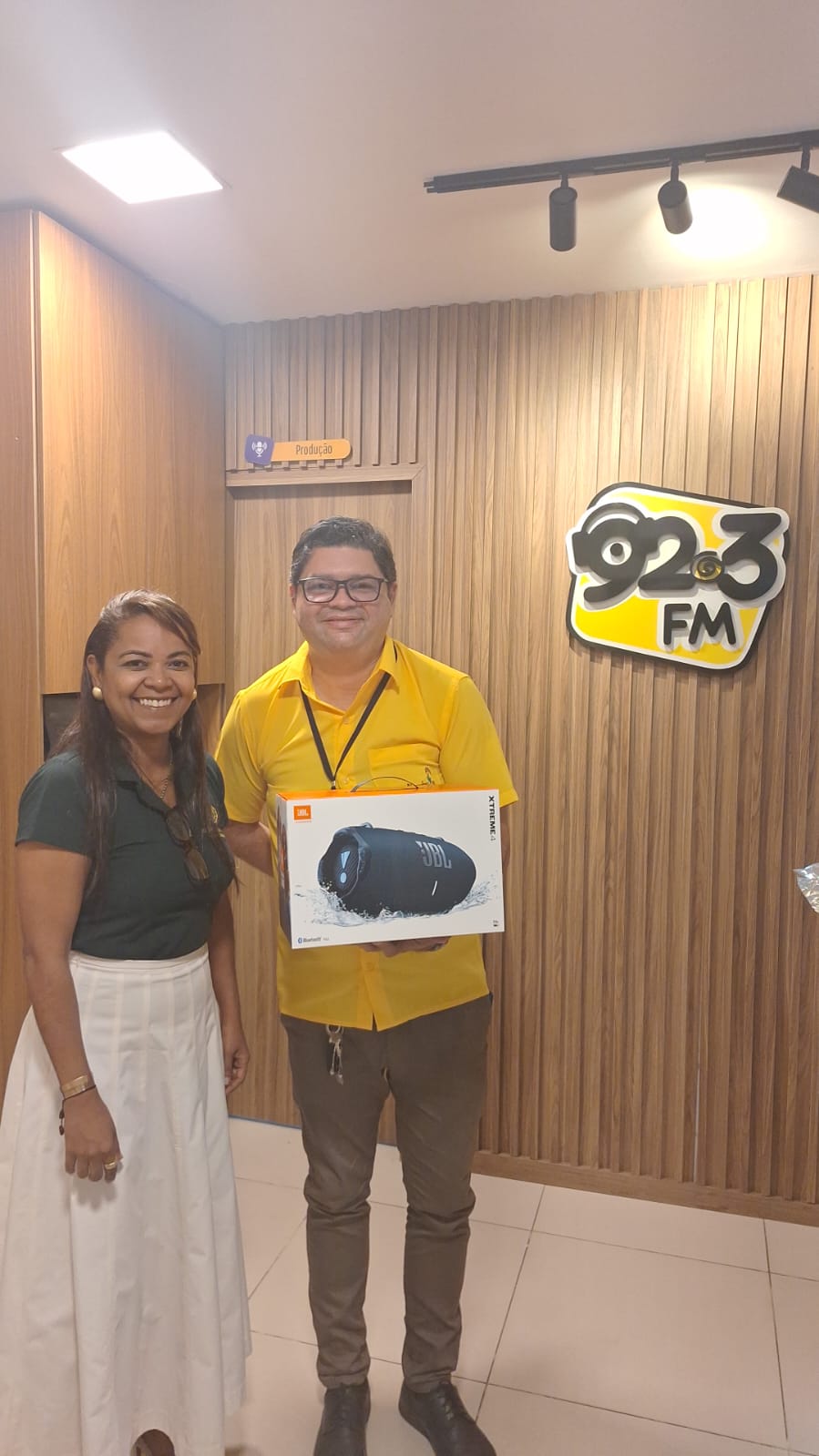 João Baima segurando a caixa da JBL Xtreme 4 na entrega do prêmio, no estúdio da 92.3 FM